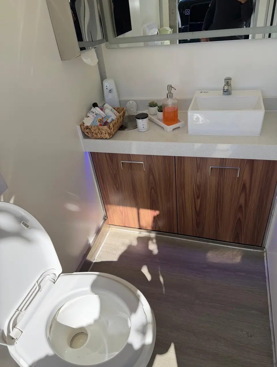 Restroom trailer vanity with vessel sink, wood cabinet and toiletries