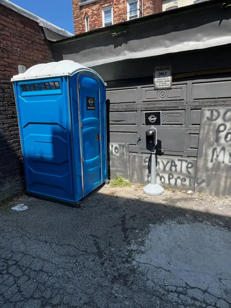 Blue porta potty set beside a building