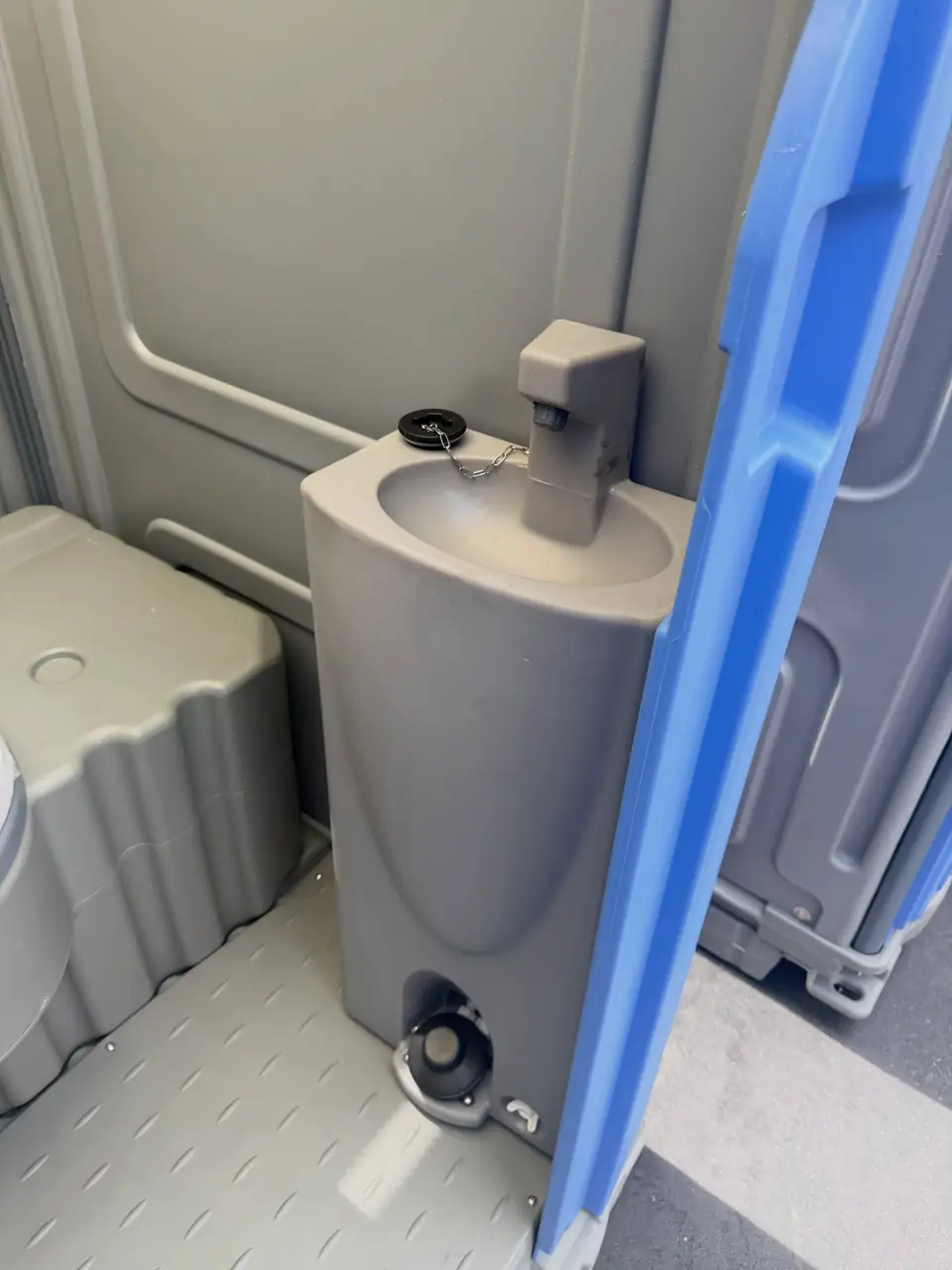 Portable toilet interior with built-in sink basin and dispenser