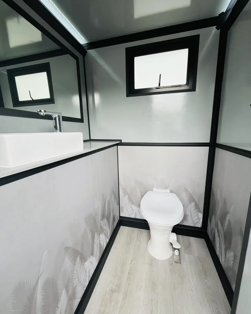 Restroom trailer room with flushing toilet, window and wood-look floor
