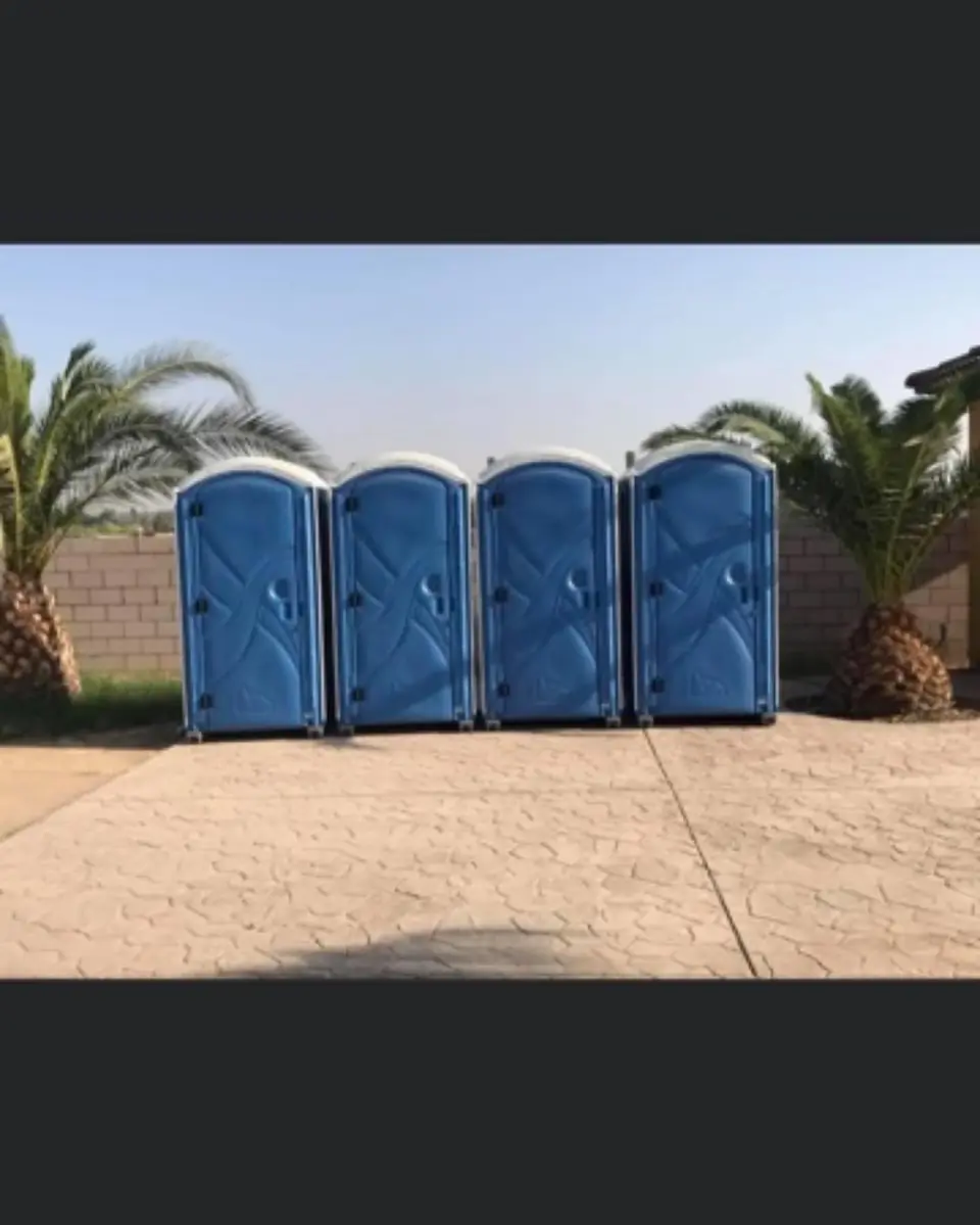 Row of four blue porta potties at an outdoor site