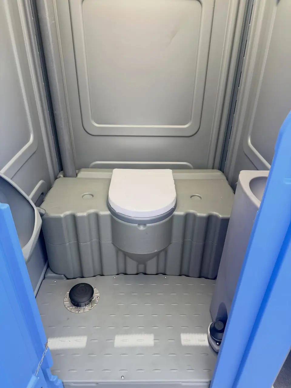Clean portable toilet interior with seat and gray floor