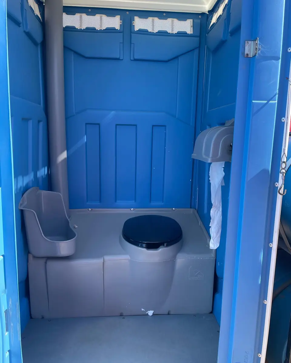 Inside a wide portable restroom with grab rail and roomy floor